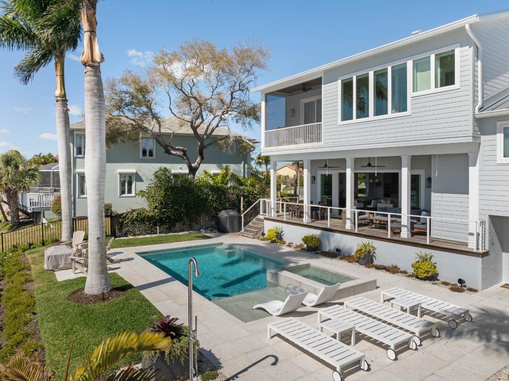 Coastal home backyard with pool, spa, and lounge chairs